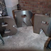 insegna a forma di lettera