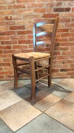 Sedia di legno con seduta in paglia intrecciata.