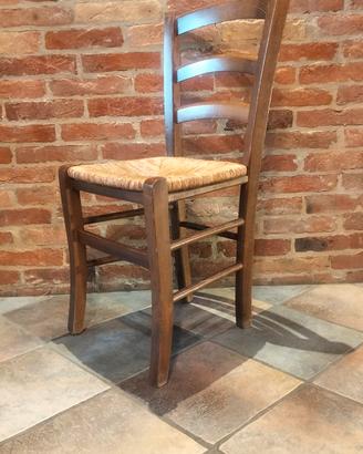 Sedia di legno con seduta in paglia intrecciata.