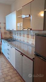 cucina usata con lavello, frigo e piano cottura