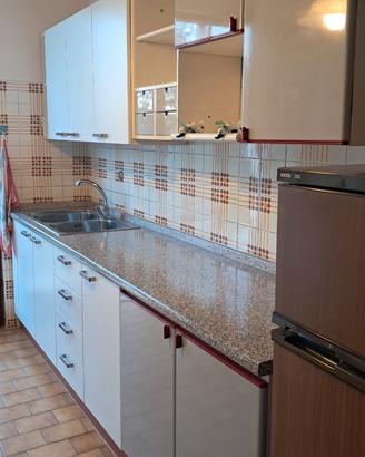 cucina usata con lavello, frigo e piano cottura