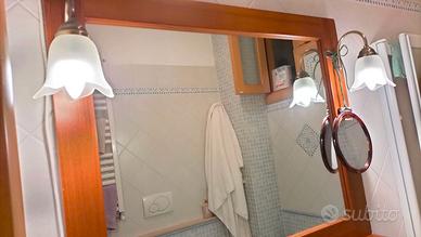 Specchio con cornice in legno e due lampade .