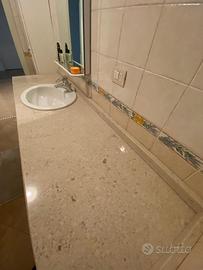 Arredo bagno piano in marmo con lavabo e lavatrice