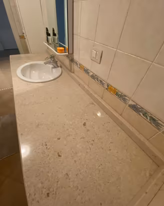 Arredo bagno piano in marmo con lavabo e lavatrice