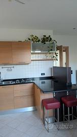 Cucina con penisola in legno chiaro con piano nero