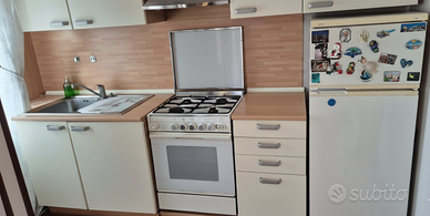 Cucina con frigorifero, forno e piano cottura