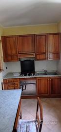 Cucina in legno con elettrodomestici, tavolo sedie