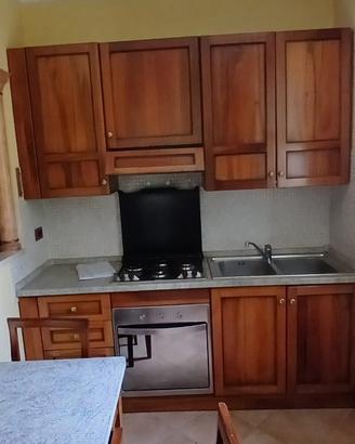 Cucina in legno con elettrodomestici, tavolo sedie