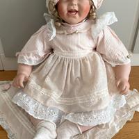 Bambola di porcellana seduta con abito rosa