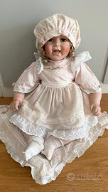 Bambola di porcellana seduta con abito rosa