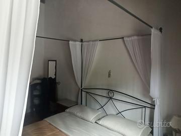 Letti in ferro battuto a baldacchino.