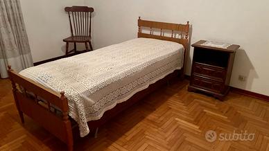Letto singolo con struttura e testiera in legno.