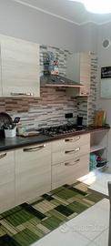Cucina con elettrodomestici, tavolo e sedie.