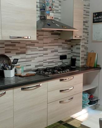 Cucina con elettrodomestici, tavolo e sedie.