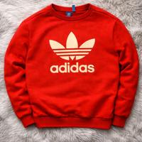 felpa rossa dell'adidas con logo bianco al centro.