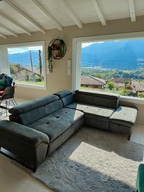 Divano con penisola, tappeto e pouf.