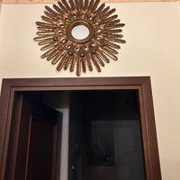 specchio con cornice dorata a raggiera