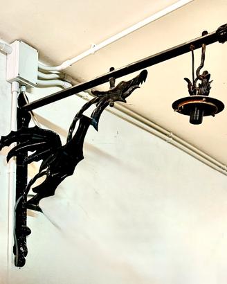 Lampada a braccio in ferro battuto colore nero.