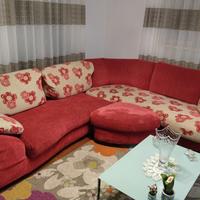 Divano angolare rosso con cuscini floreali.
