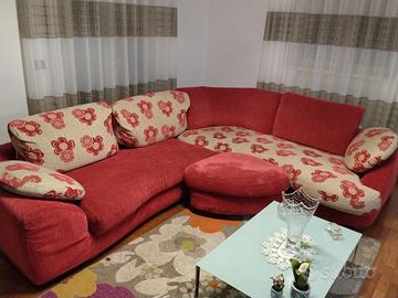 Divano angolare rosso con cuscini floreali.