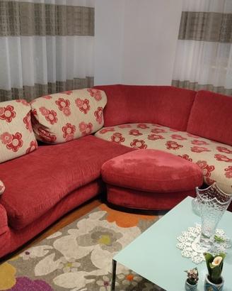 Divano angolare rosso con cuscini floreali.