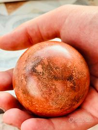 Dorodango rosso con striature nere lucidato a mano