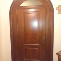 Porta in legno ad arco con bugne e vetro superiore