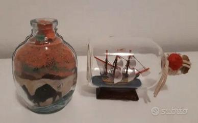 Bottiglie in vetro con nave e sabbia
