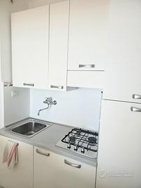 Cucina bianca completa con lavello e piano cottura