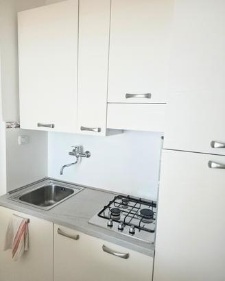 Cucina bianca completa con lavello e piano cottura