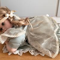 Bambola di porcellana sdraiata con abito verde