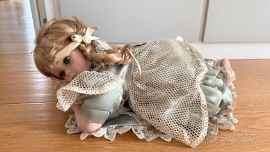 Bambola di porcellana sdraiata con abito verde