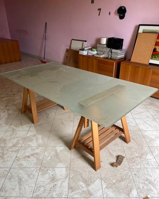 Scrivania in vetro con cavalletti in legno.