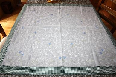 Copritavolo quadrato con ricamo floreale.