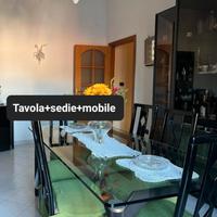 tavola in cristallo con sedie e mobile