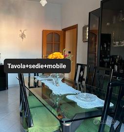 tavola in cristallo con sedie e mobile