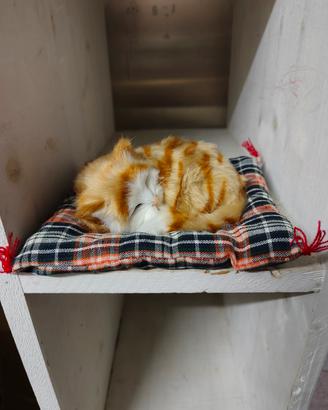 Gatto peluche realistico addormentato su cuscino