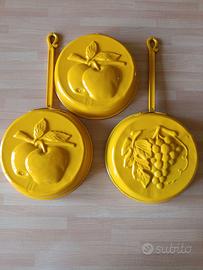 Stampi vintage in metallo smaltato giallo.