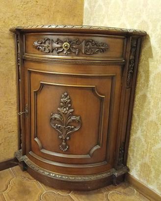 Angoliera in legno con decorazioni in rilievo.