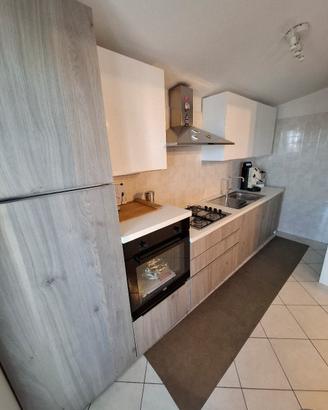 Cucina con elettrodomestici e tavolo living