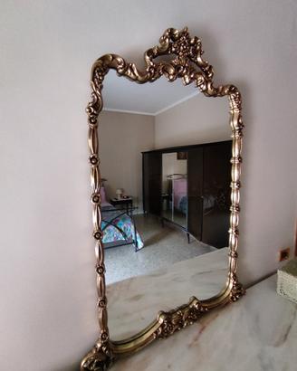 Specchio con cornice dorata in stile antico.