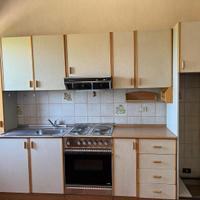 Cucina completa in legno chiaro con forno e piano