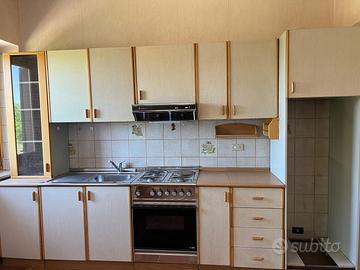 Cucina completa in legno chiaro con forno e piano