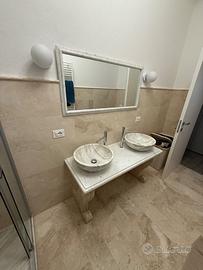 Lavandino con due vasche in travertino e marmo.