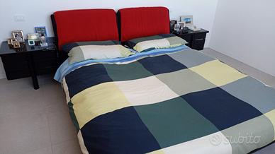 Letto imbottito e comò in legno nero laccato