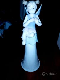 Bambina con le ali seduta su una campana di porcel