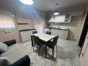 Cucina con credenza, tavolo con sedie e 2 divani