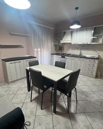 Cucina con credenza, tavolo con sedie e 2 divani