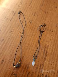 Set di due collane con cordino nero e ciondoli.  -