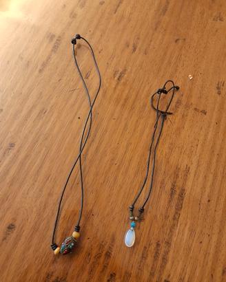 Set di due collane con cordino nero e ciondoli.  -